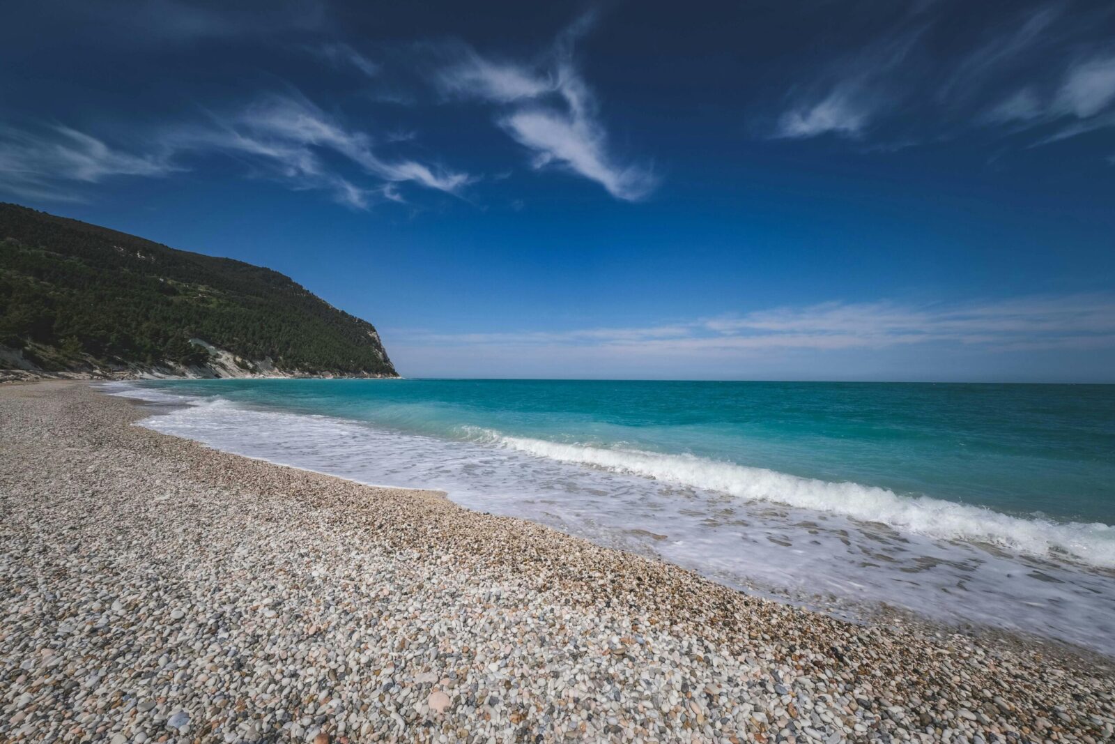 Peaceful pebble beach and turquoise ocean against a clear blue sky. Ideal for travel and nature themes.